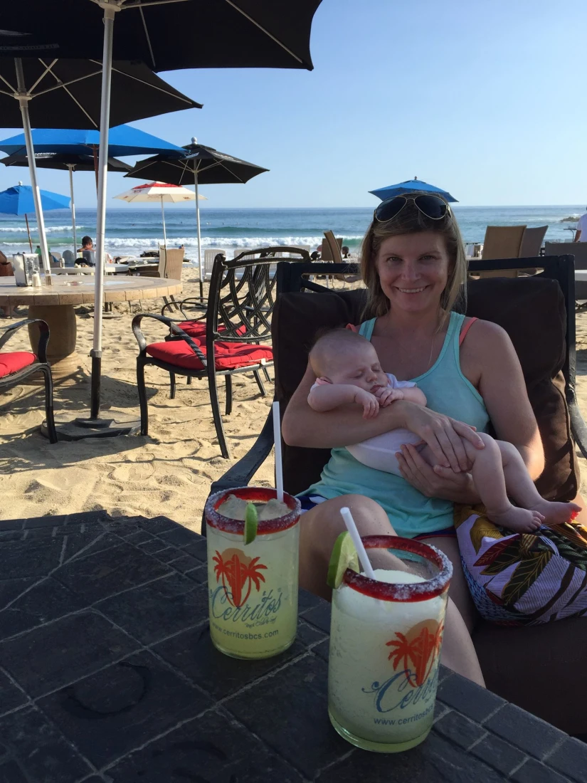 Travel advisor Jena Krinock with baby sittting at a table with drinks at Playa Los Cerritos