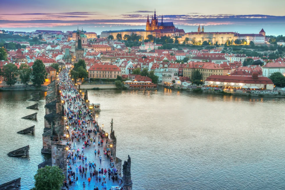 An arial view of city city covering buildings, river and people passing through the bridge over the river