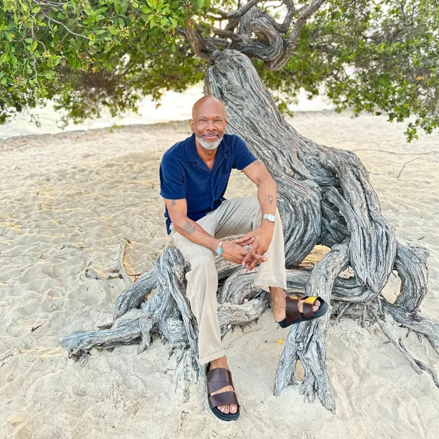 Travel advisor posing in a blue shirt sitting on a tree trunk