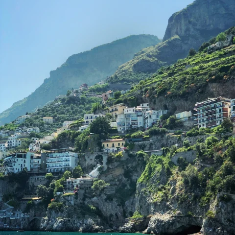 buildings on the side of a cliff near water during daytime