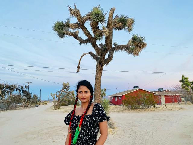 Fora Sophiya Neupane Travel Agent wearing black dress standing in front of a Joshua Tree