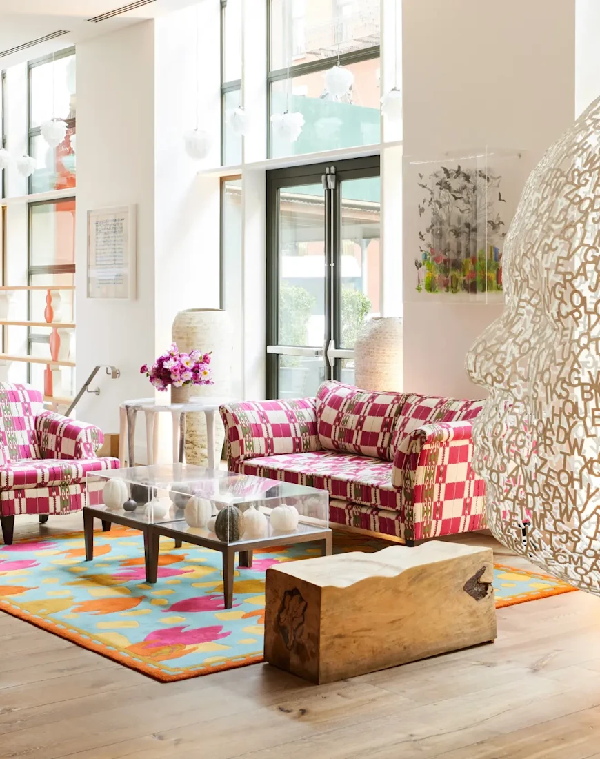 a large sculpture of a head in an art-filled lobby with pink couches