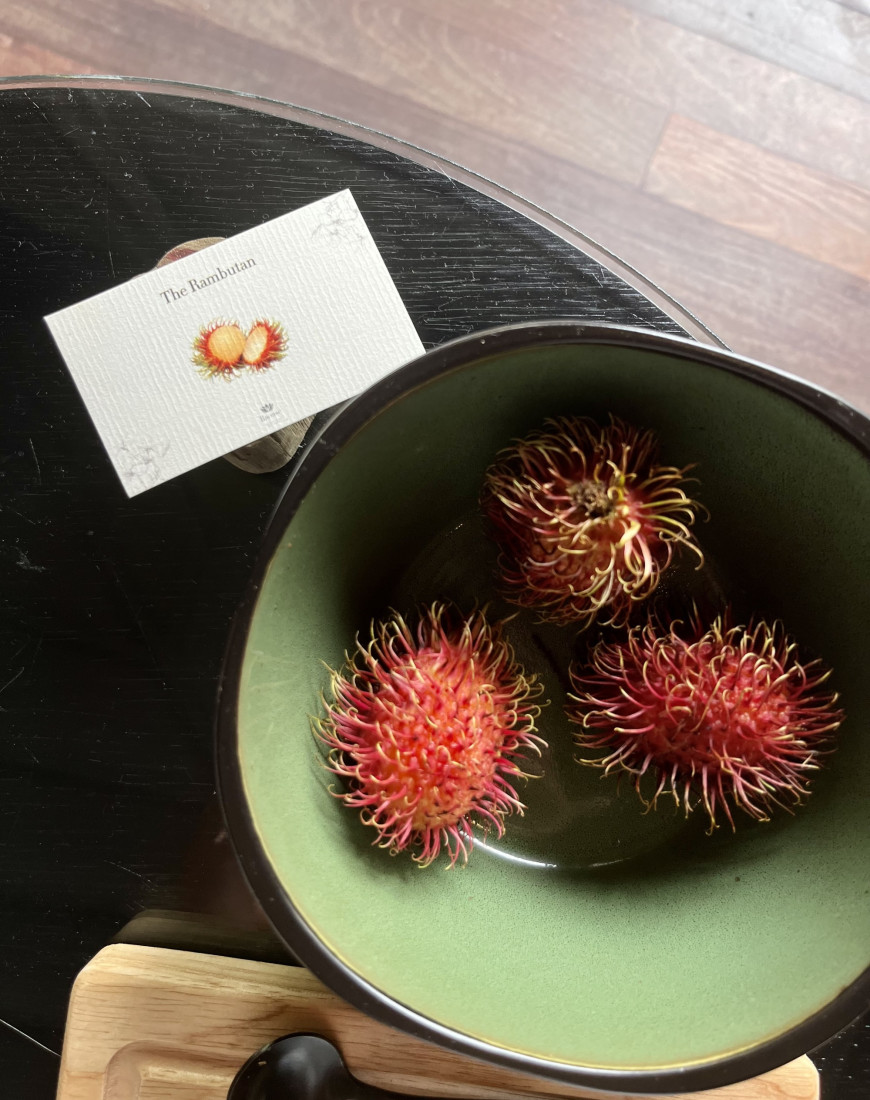 A bowl of rambutan fruit, a red and spiky fruit