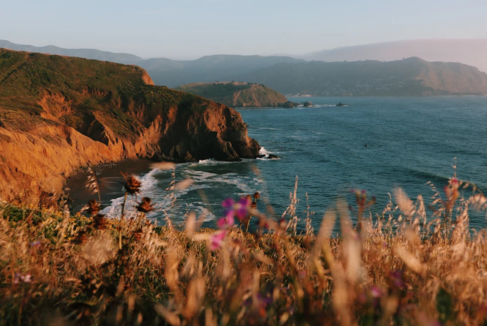 Body of water next to steep cliffs during sunset