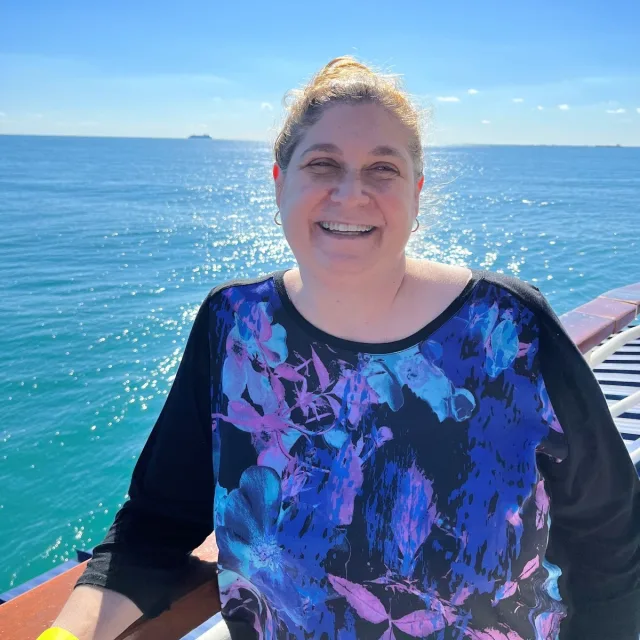 Travel advisor Andrea Bowman smiles on a cruise ship balcony.