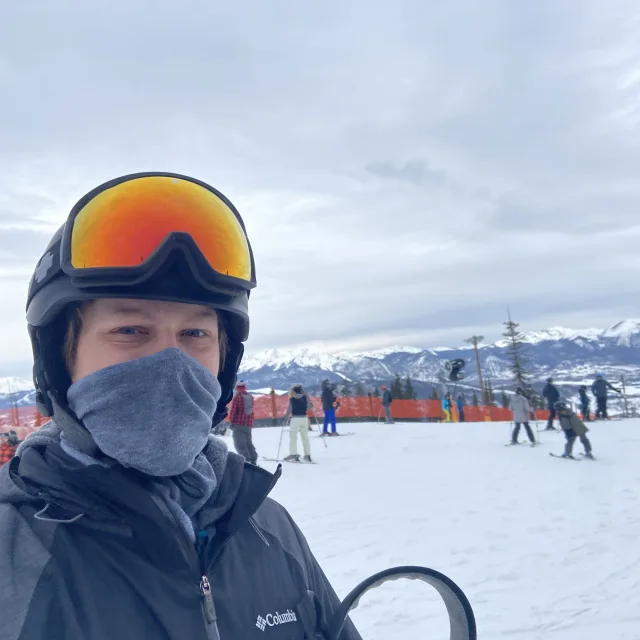 Travel Advisor Caleb Esser wears orange ski goggles on the top of a snowy mountain