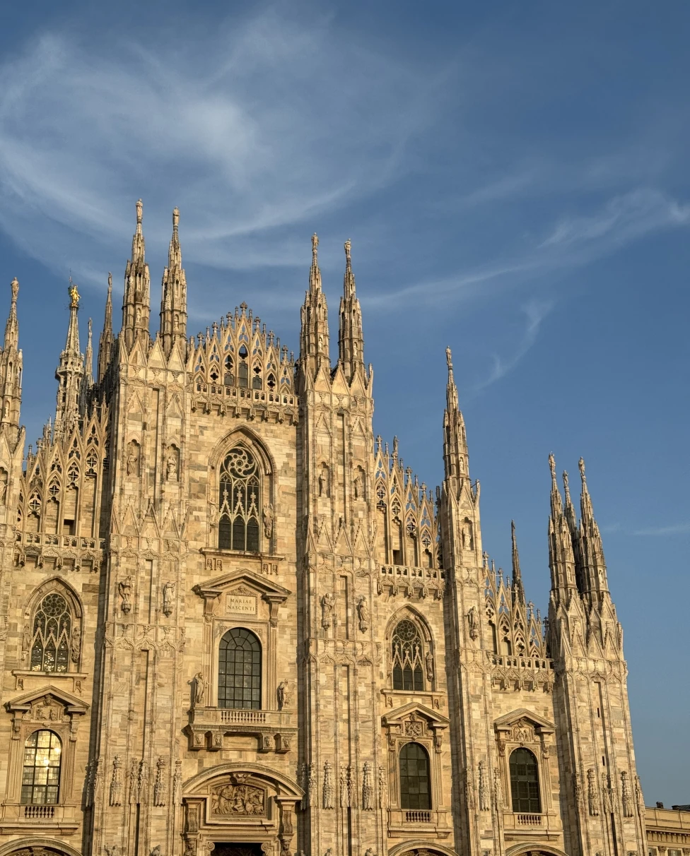 A white gothic church opening up to square at Duomo Cathedral Square in Milan, Italy.