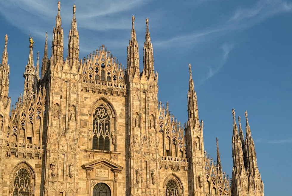 A white gothic church opening up to square at Duomo Cathedral Square in Milan, Italy.