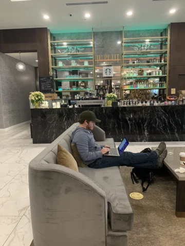A coffee bar area in a hotel with a person working on a gray couch