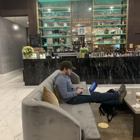 A coffee bar area in a hotel with a person working on a gray couch