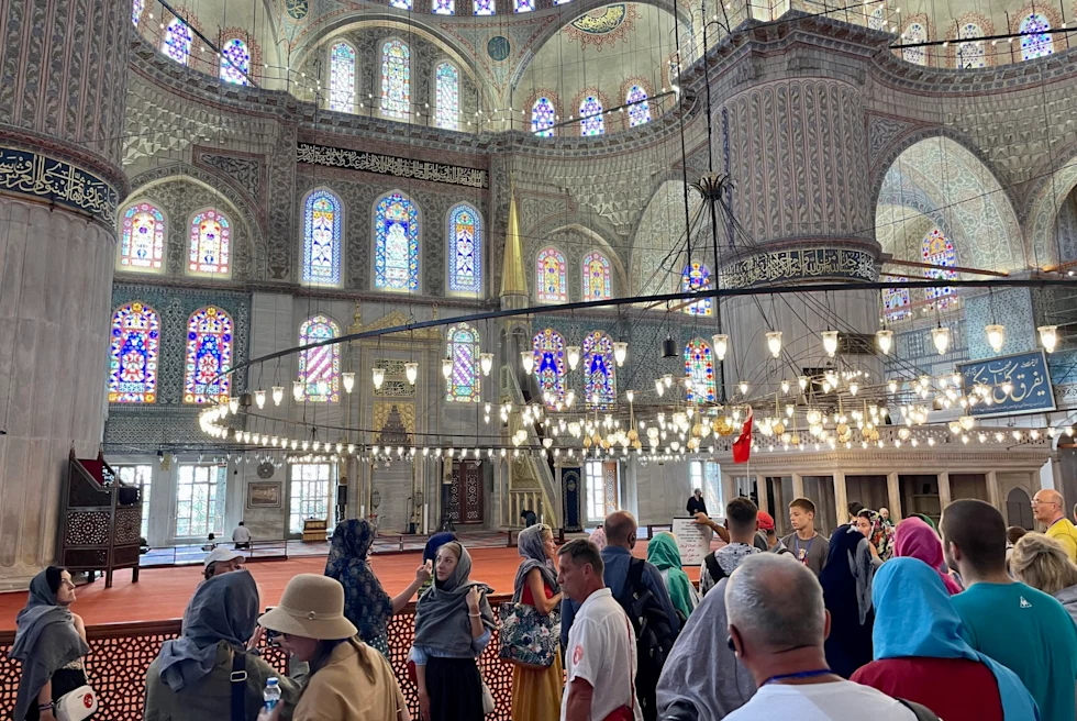 Inside of a mosque with people in it.