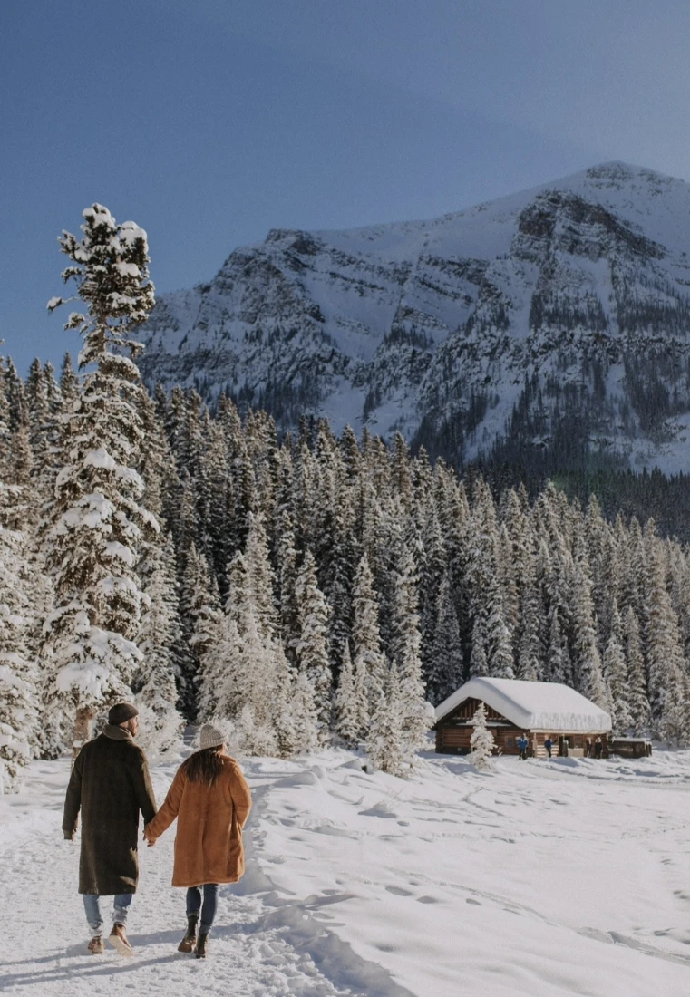 two people in coats walk on a snow mountain