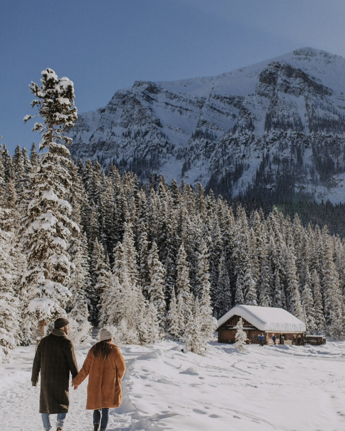 two people in coats walk on a snow mountain
