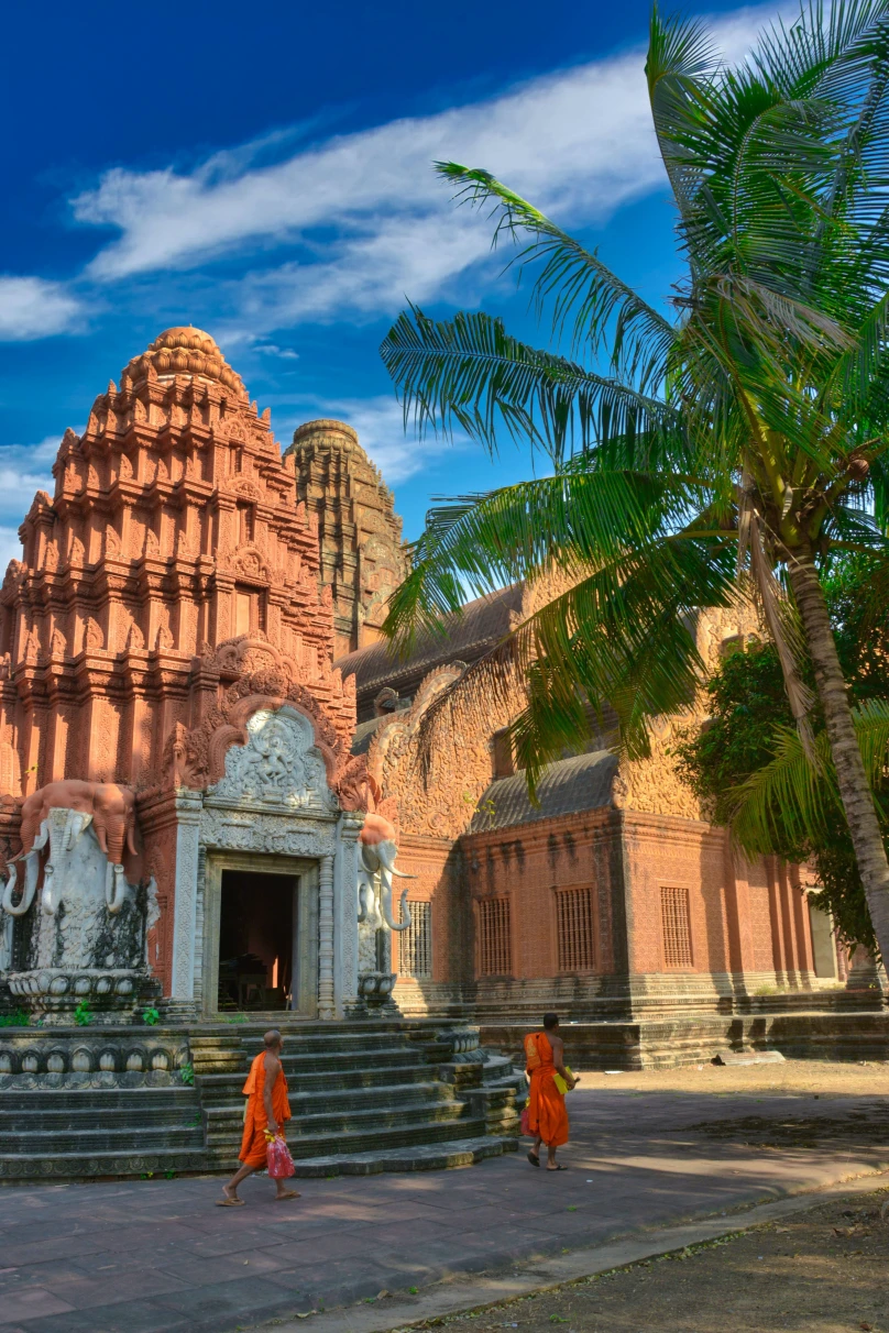 two monks walking next to temples and palm trees