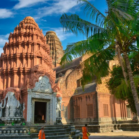 two monks walking next to temples and palm trees