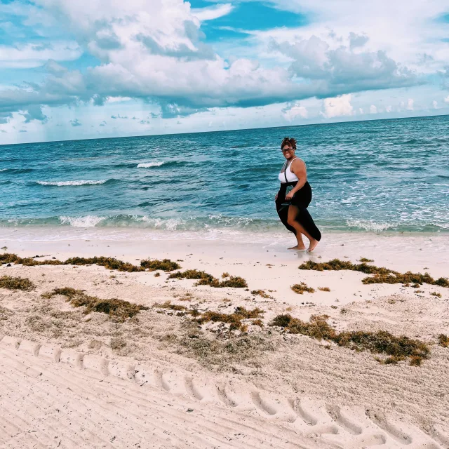 Crystal Johnson on the sandy beach wearing a black and white dress on a cloudy day
