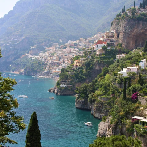 body of water next to cliff with houses during daytime