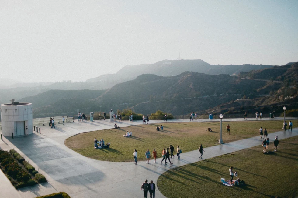 views of the hills of Los Angeles on a grassy plaza of a museum dotted with visitors 