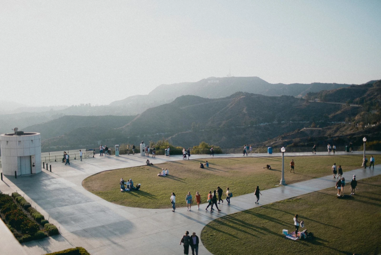 views of the hills of Los Angeles on a grassy plaza of a museum dotted with visitors 