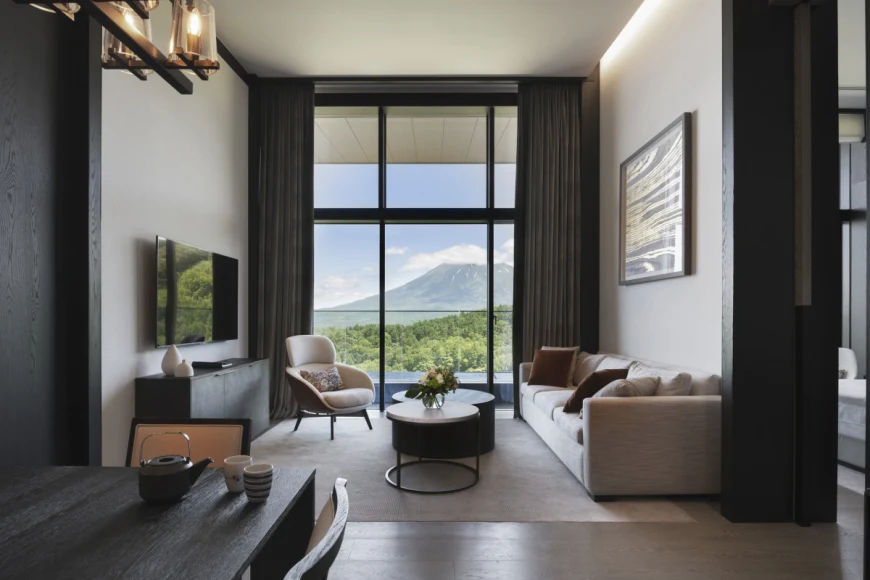 sleek hotel room with floor-to-ceiling windows overlooking a green mountain