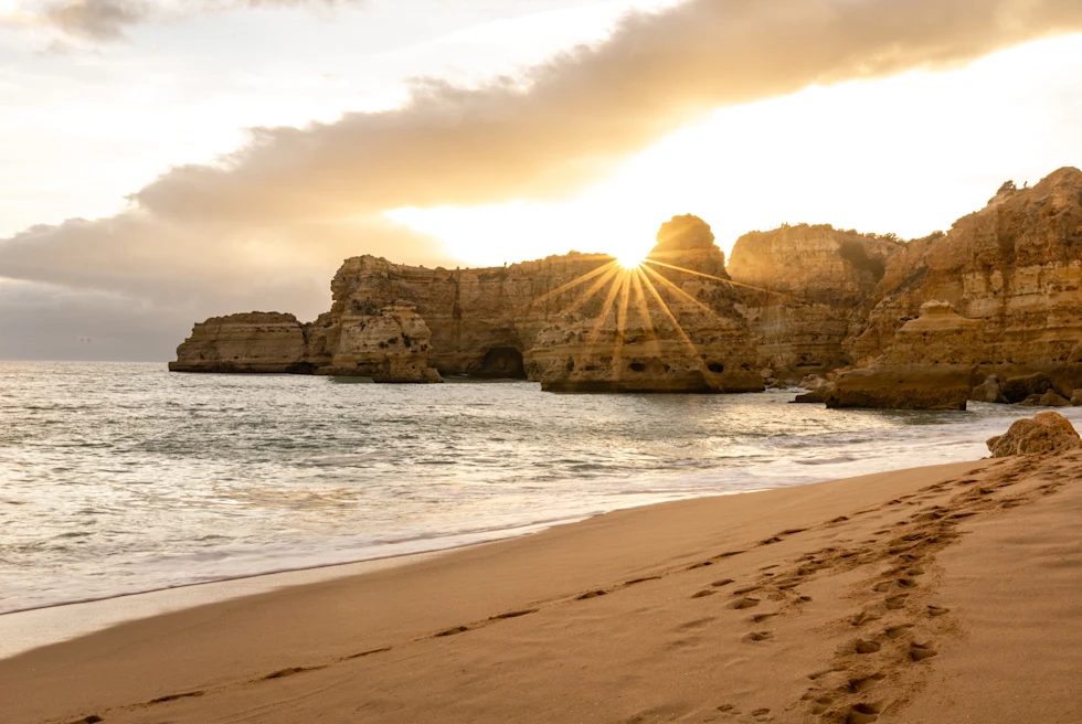 A beach with mountain rocks at sunset.