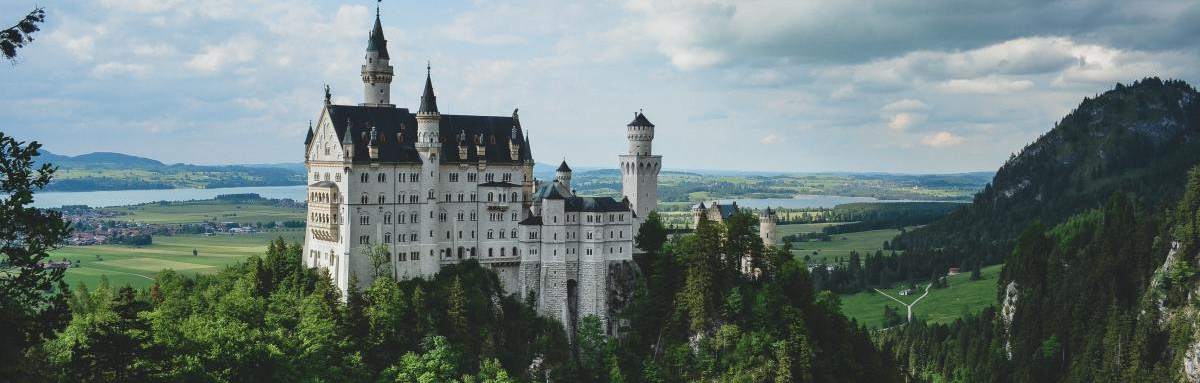 Towering castle in Bavaria among rolling hills in Germany.
