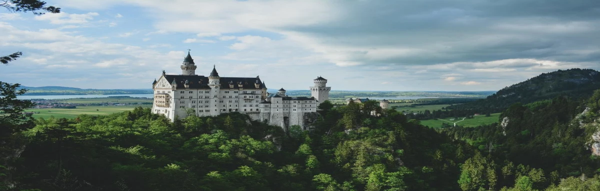 Towering castle in Bavaria among rolling hills in Germany.