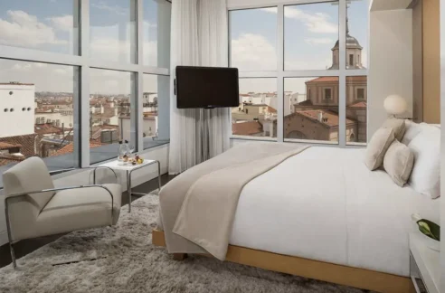 A corner room at the ME Madrid Reina Victoria with floor-to-ceiling windows overlooking the city.
