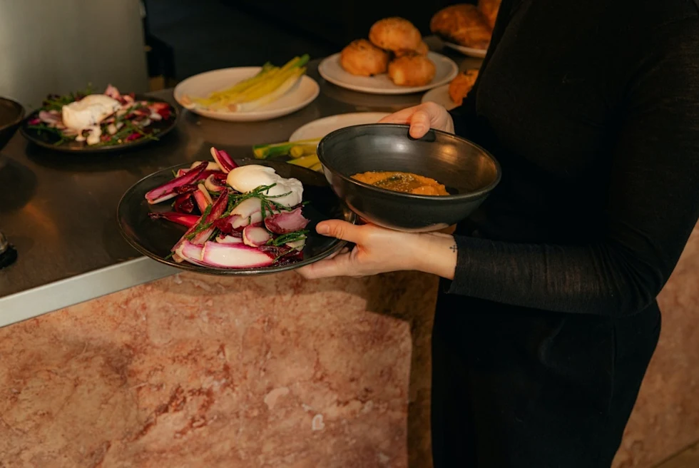 woman holding black plates filled with vegetables