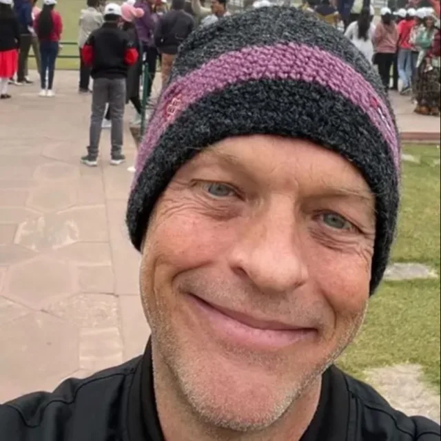 Travel Advisor Andrew Eisenmann in a black and purple wool hat taking a selfie outdoors. 