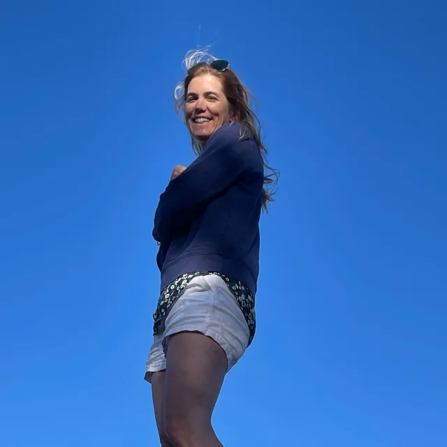 woman wearing black shirt and jean shorts with blue skies