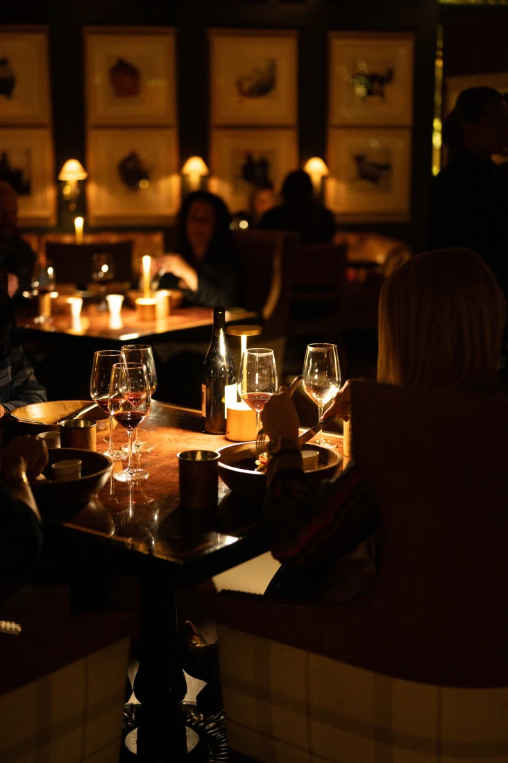 people enjoying dinner and wine in a dark restaurant
