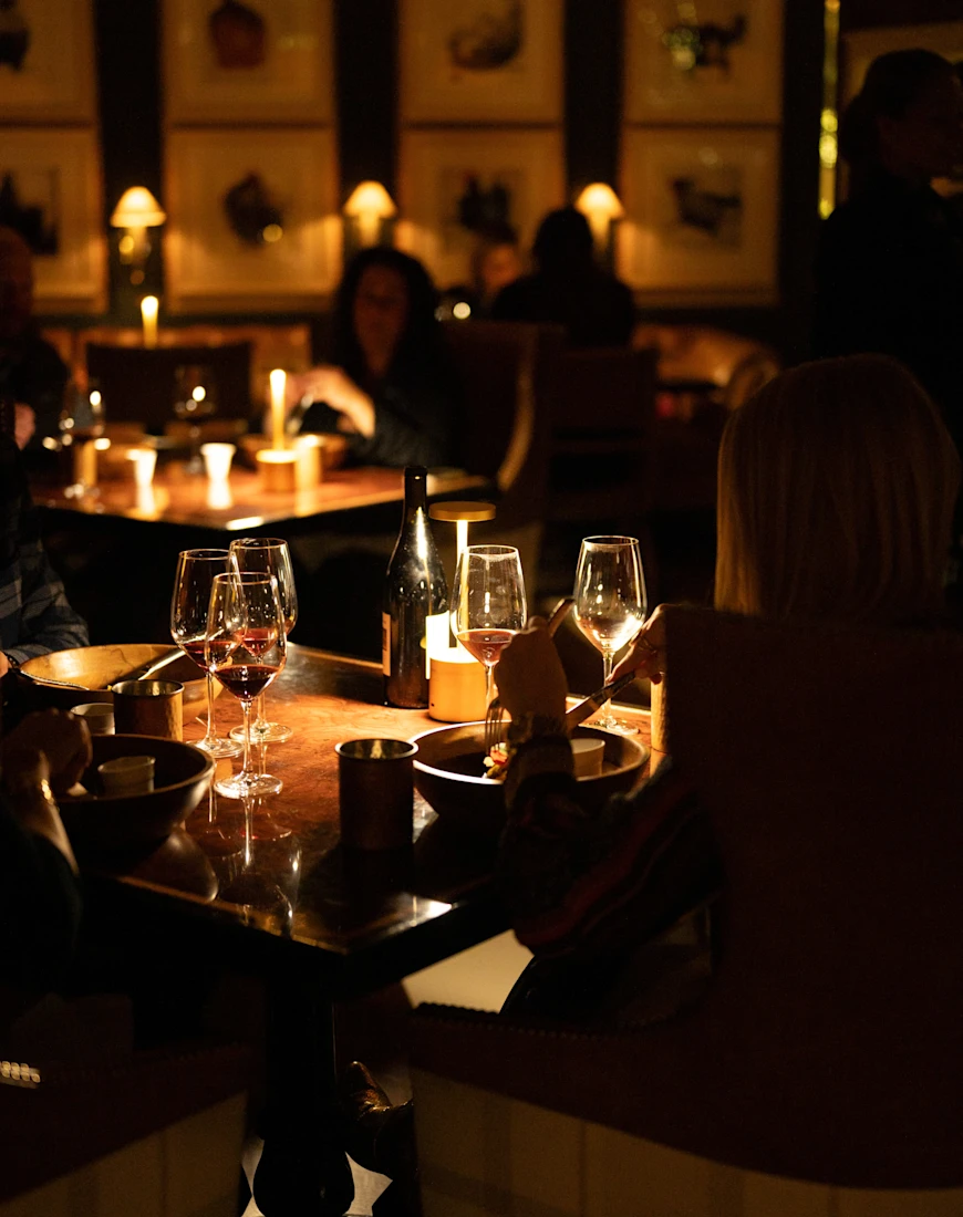 people enjoying dinner and wine in a dark restaurant