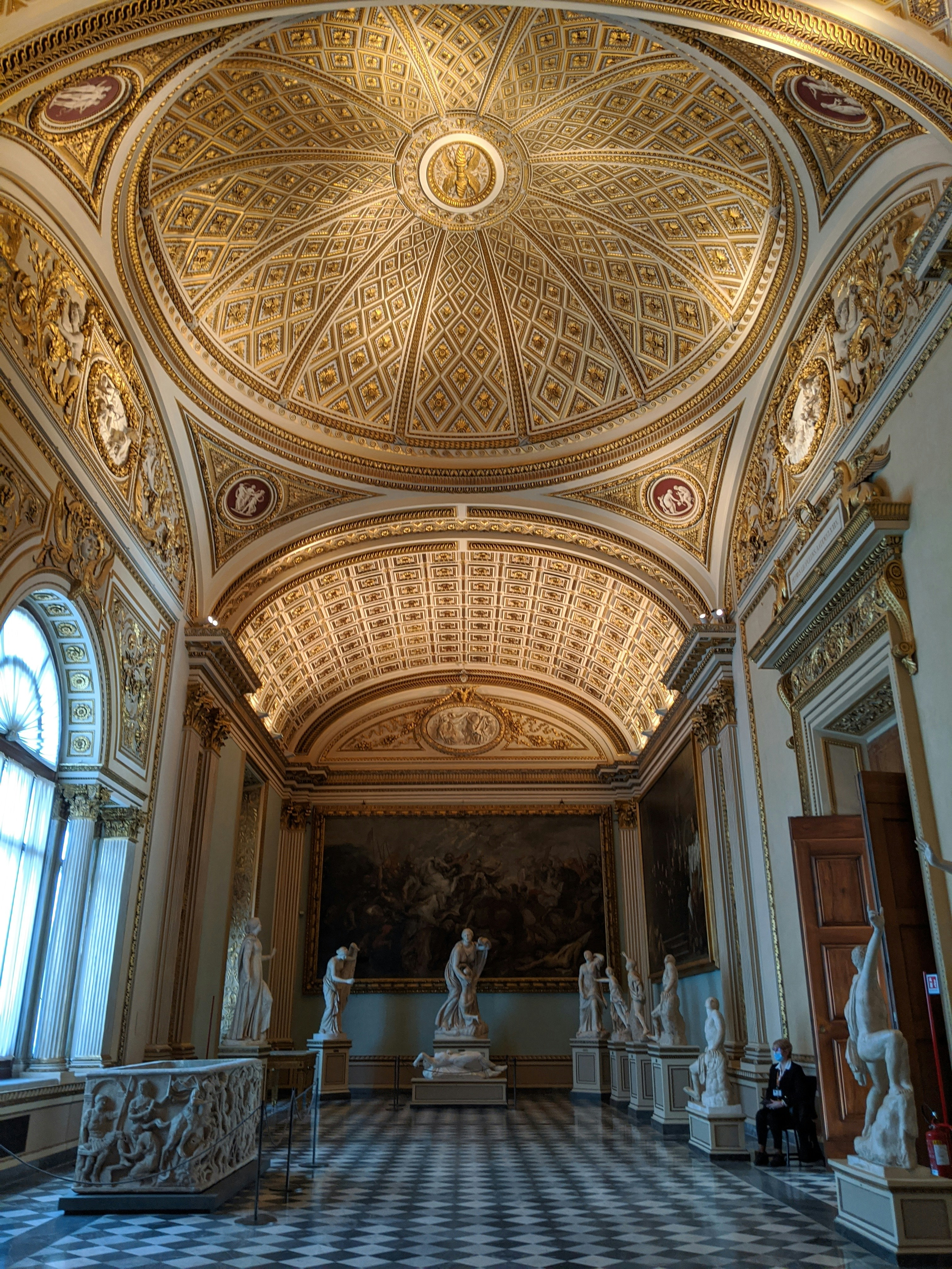 arched ceiling in a museum with colorful ceiling details and tiled floor and statues