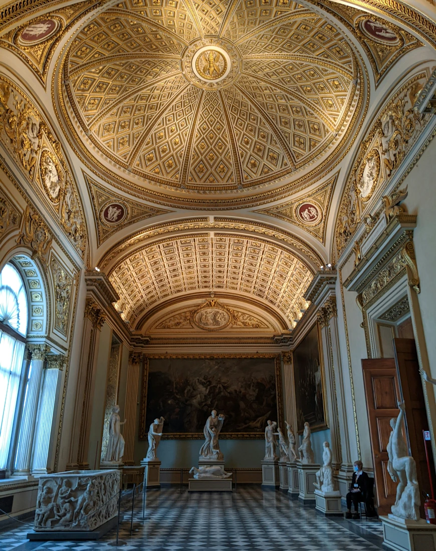 arched ceiling in a museum with colorful ceiling details and tiled floor and statues