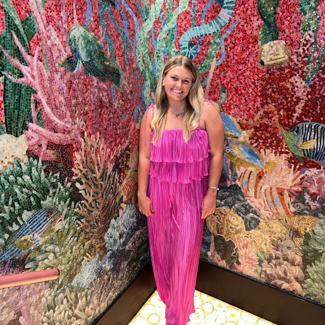 brittany in pink dress with colorful art in the background. 