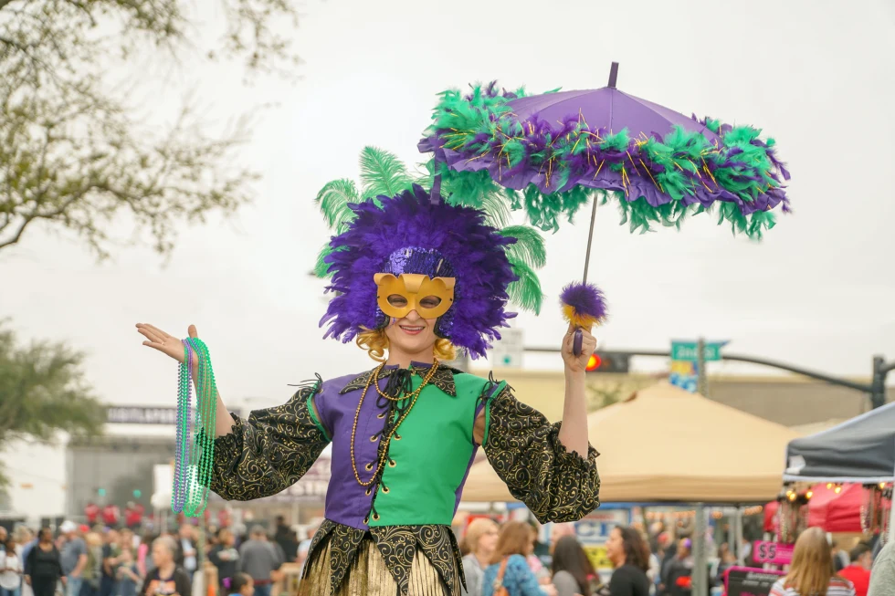 A man with a masquerade in green and purple dress on the street