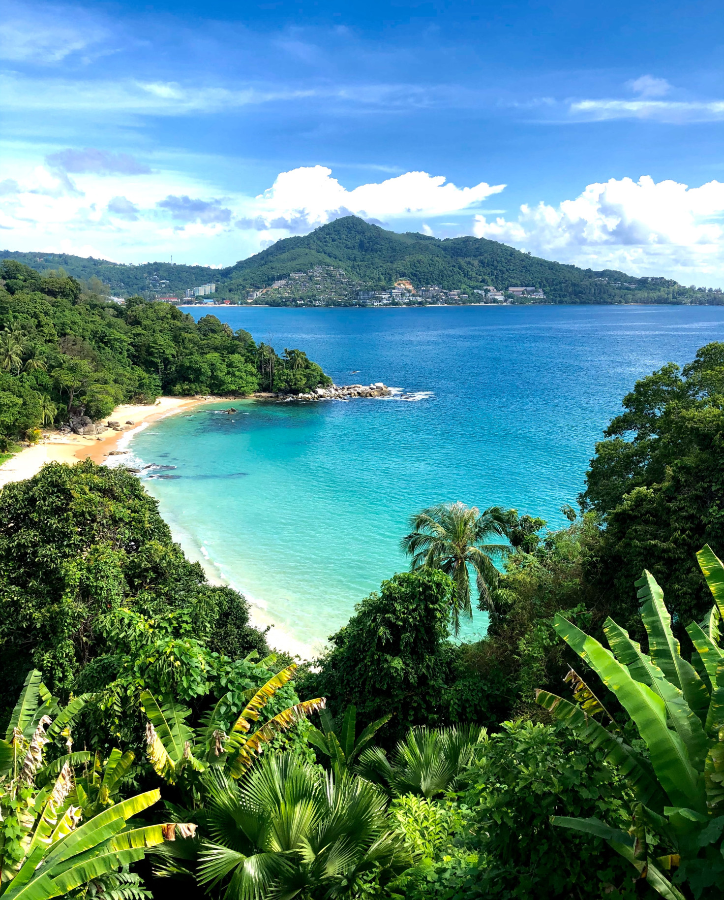 beach next to blue water with mountain in background during daytime