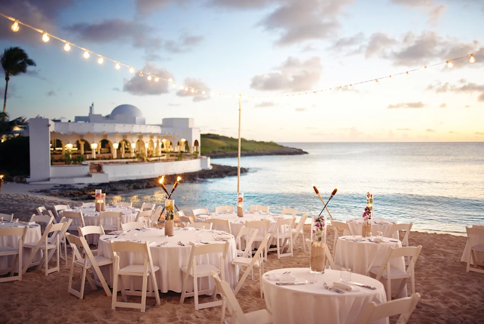 white tables and chairs on the beach next to the water during daytime