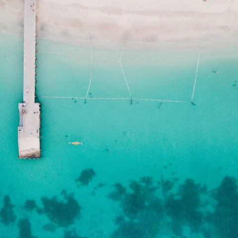 An aerial view of Saint Martin with crystal blue water and a white dock.