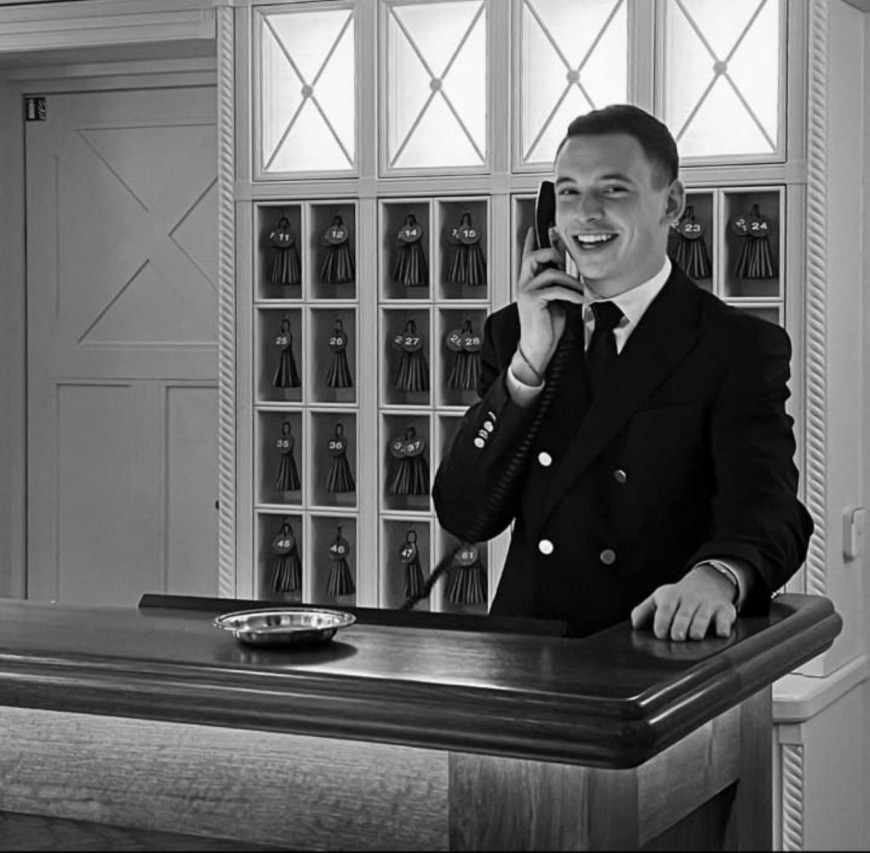 a black-and-white photo of a man speaking in a telephone at a desk