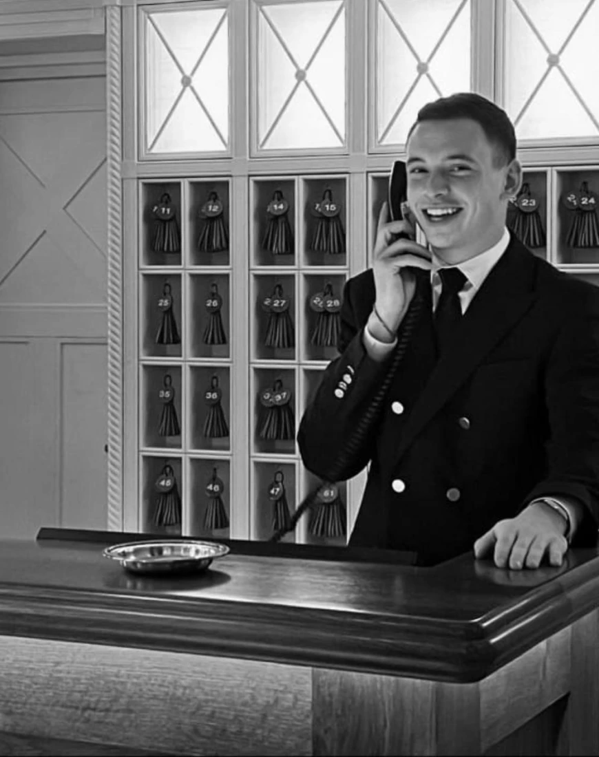 a black-and-white photo of a man speaking in a telephone at a desk