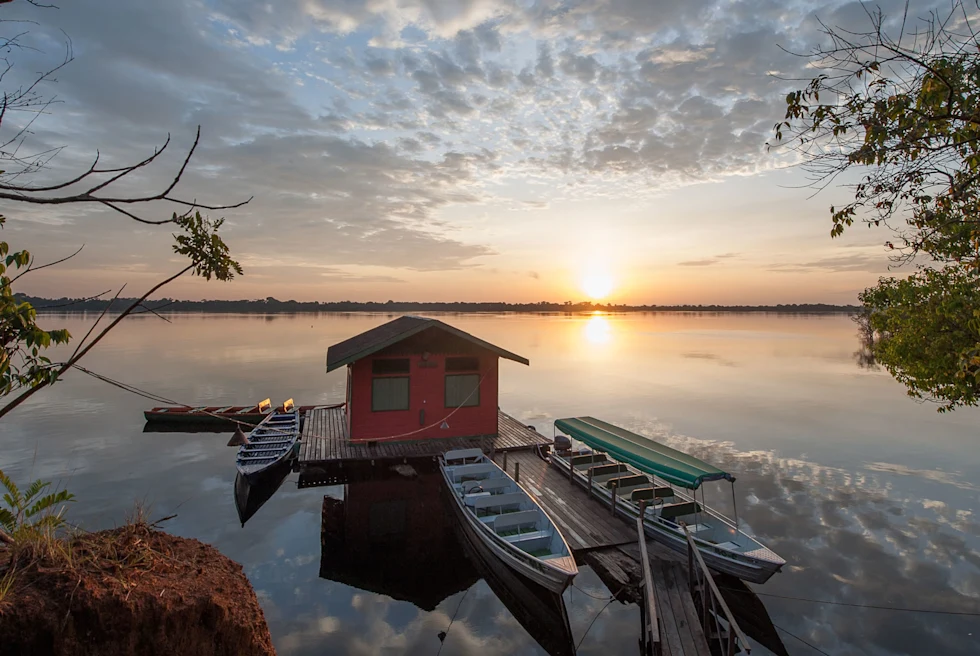 sunrise view over the still water reflecting the clouds with a dock and several boats in the foreground