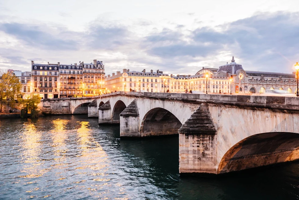 view from across a bridge on Paris' river Seine with lights sparkling in building windows