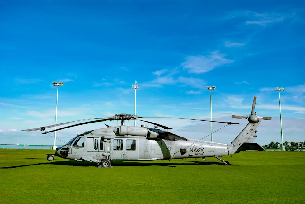 white and blue airplane on green grass with blue skies