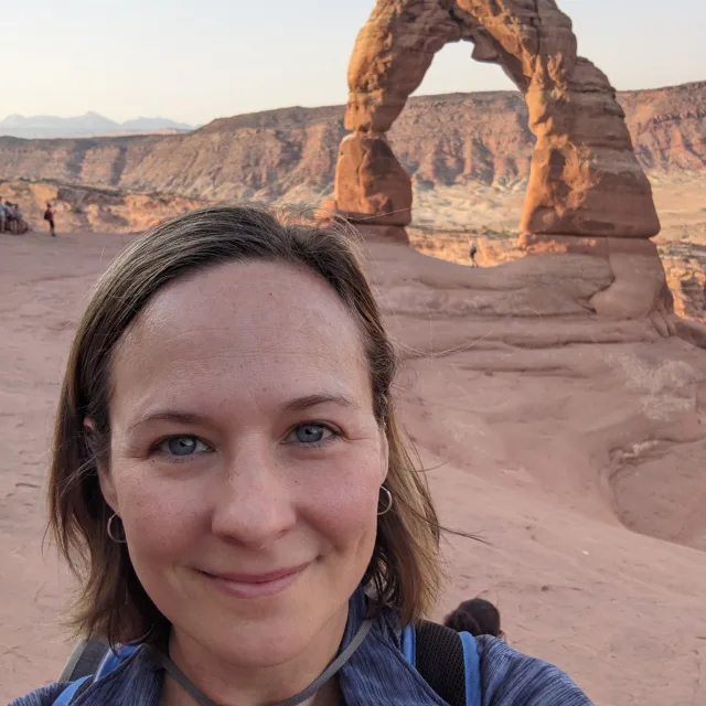 Travel advisor Lauren Johanson with short brown hair smiling in front of a rock arch formation