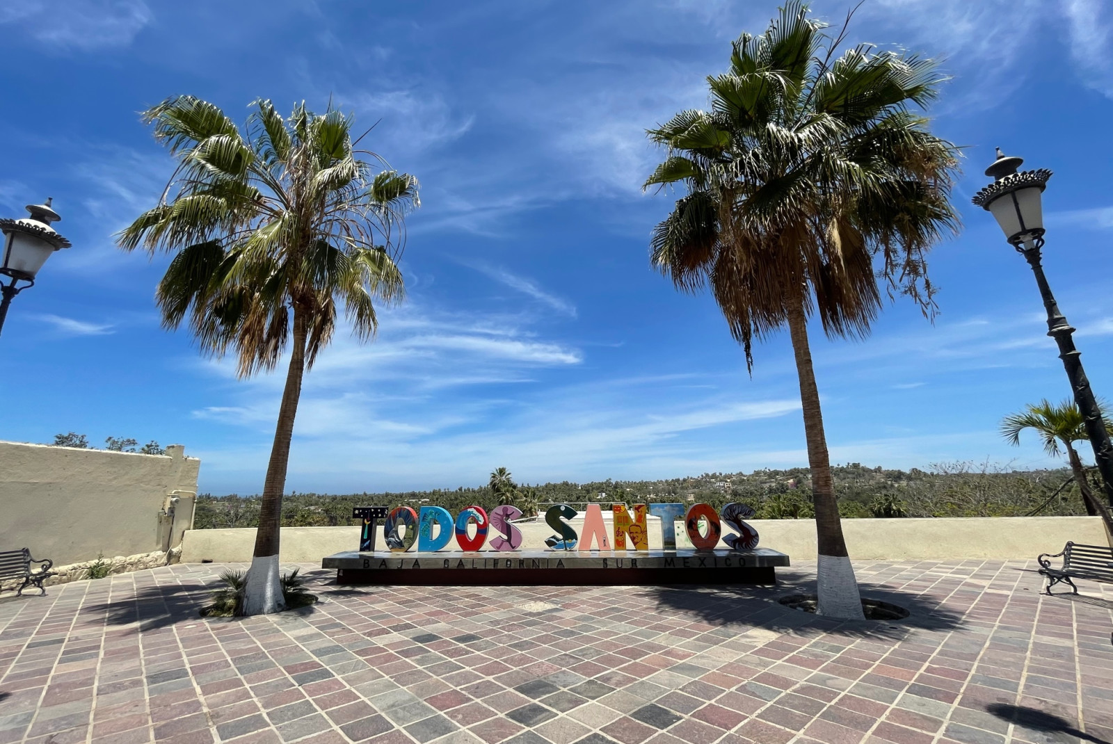 colorful sign that reads Todos Santos with two palm trees framing it