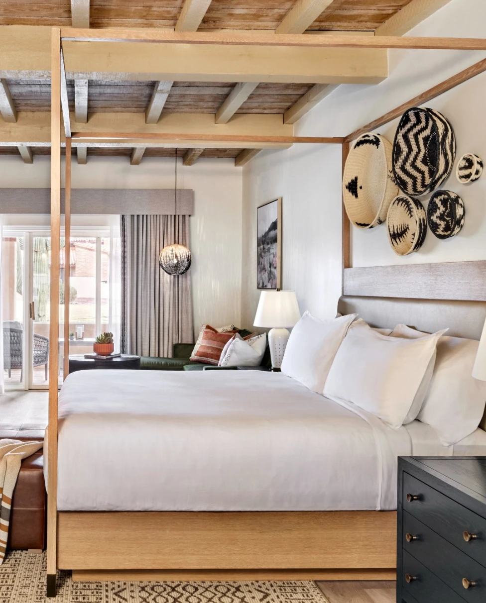 white bed in a hotel room with a fireplace and wooden ceiling beams