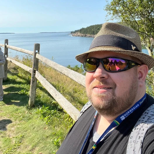 Travel advisor posing on a lakeside wearing a hat