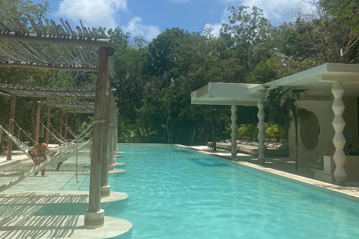 Blue pool with beach hammocks on either side.